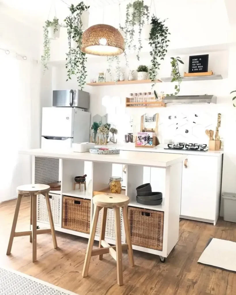 A modern small kitchen design with a white rolling island and abundant hanging plants.