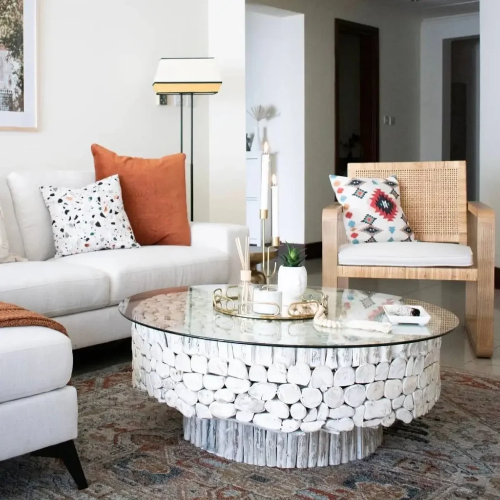 A chic living room with a white sofa, a unique whitewashed log coffee table, and a rattan accent chair.