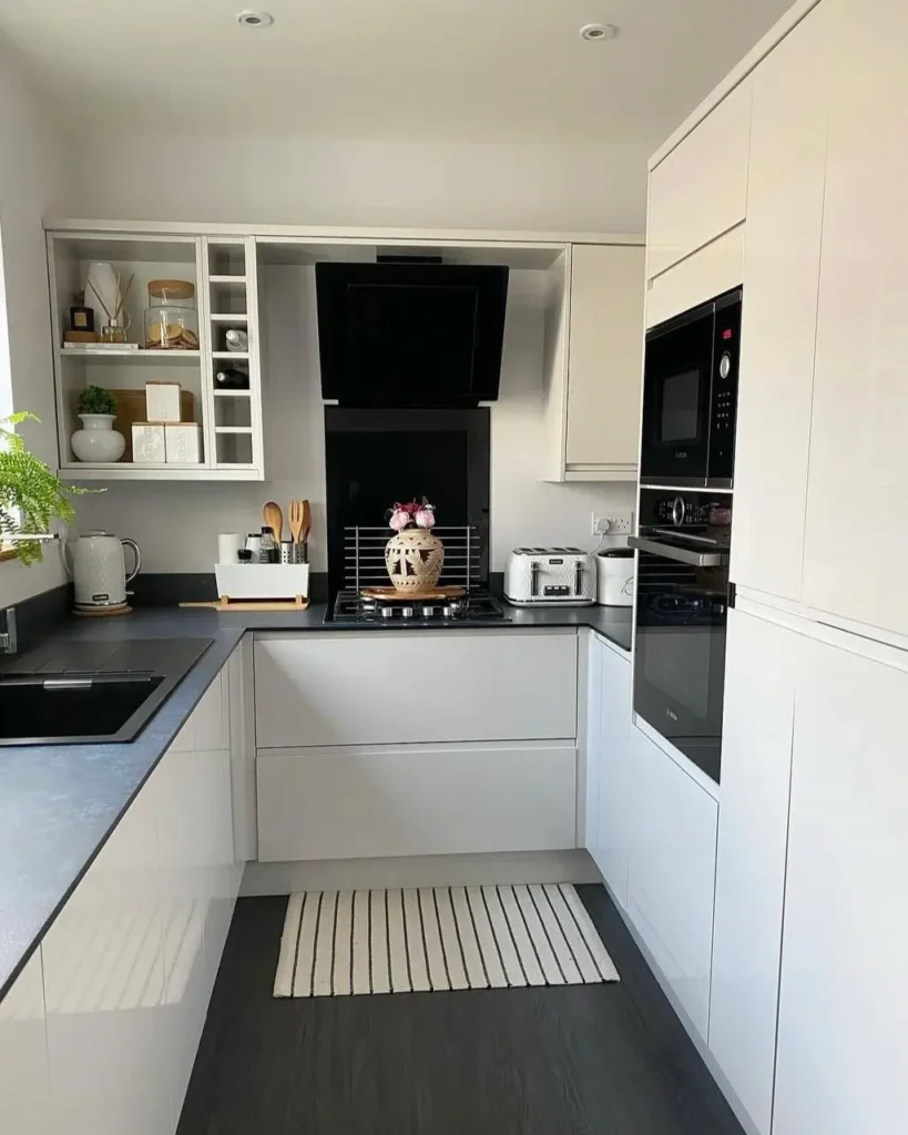 A modern U-shaped kitchen with glossy white cabinets and dark countertops.