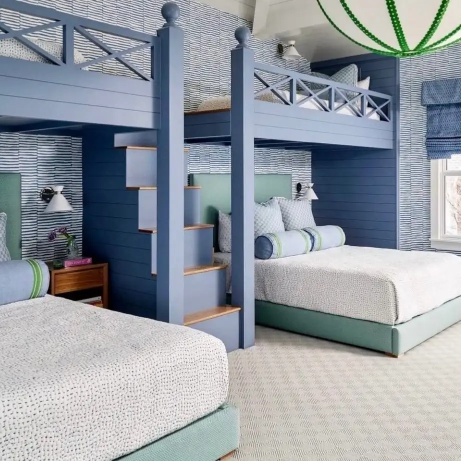 A coastal kids' bedroom with custom blue built-in bunk beds, striped wallpaper, and a large lantern pendant.
