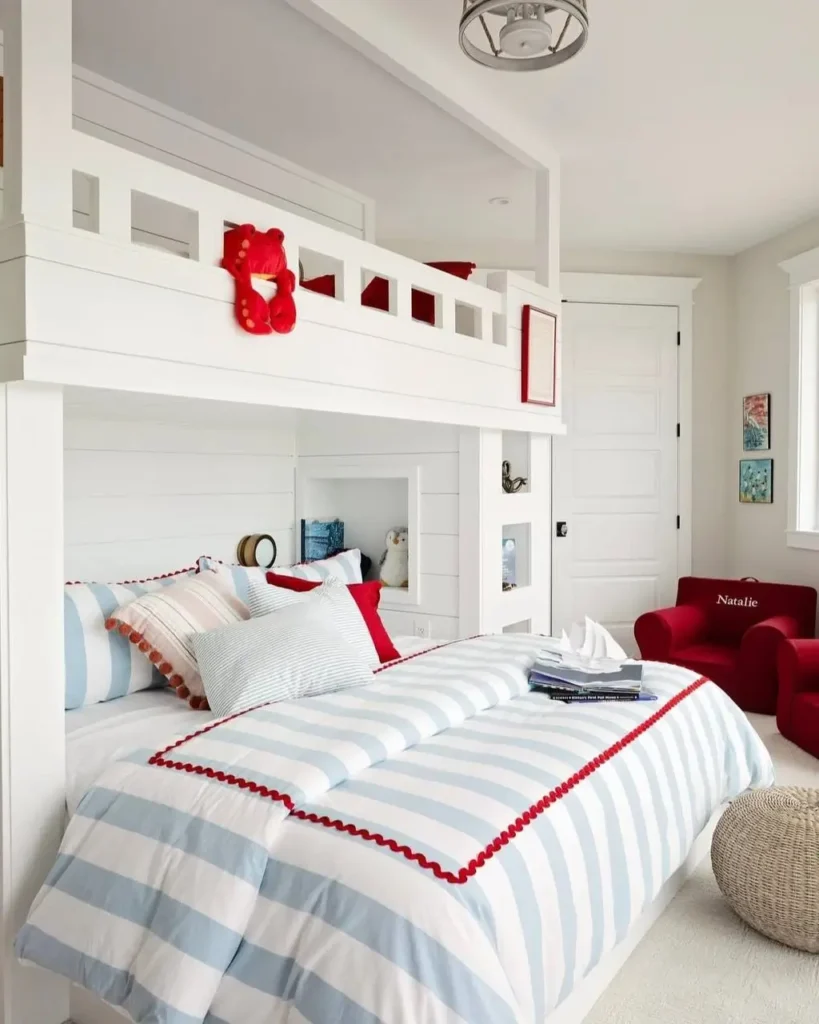 A kids' nautical themed bedroom with a white loft bed, blue and white striped bedding, and red accents.