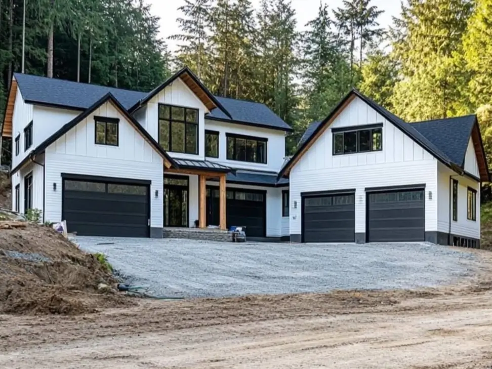 A modern white farmhouse with black trim and a matching detached garage, featuring warm wood accents at the entryway.