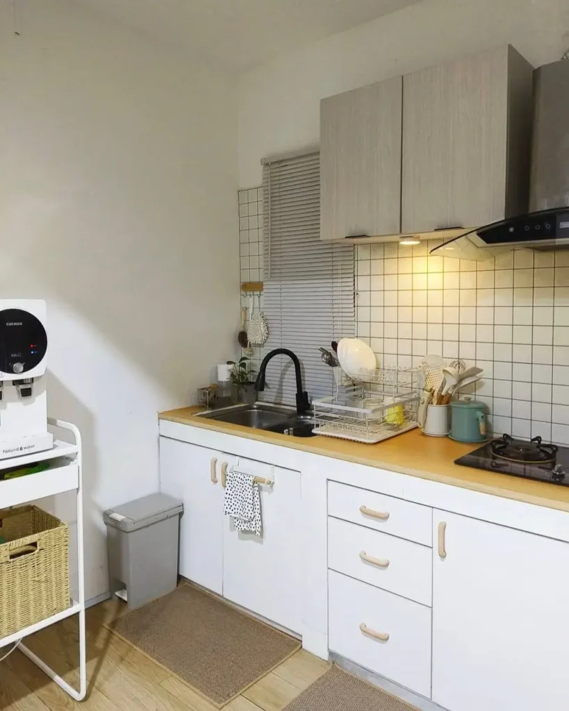 A simple single-wall kitchen with white cabinets, a wood countertop, and a grid tile backsplash.