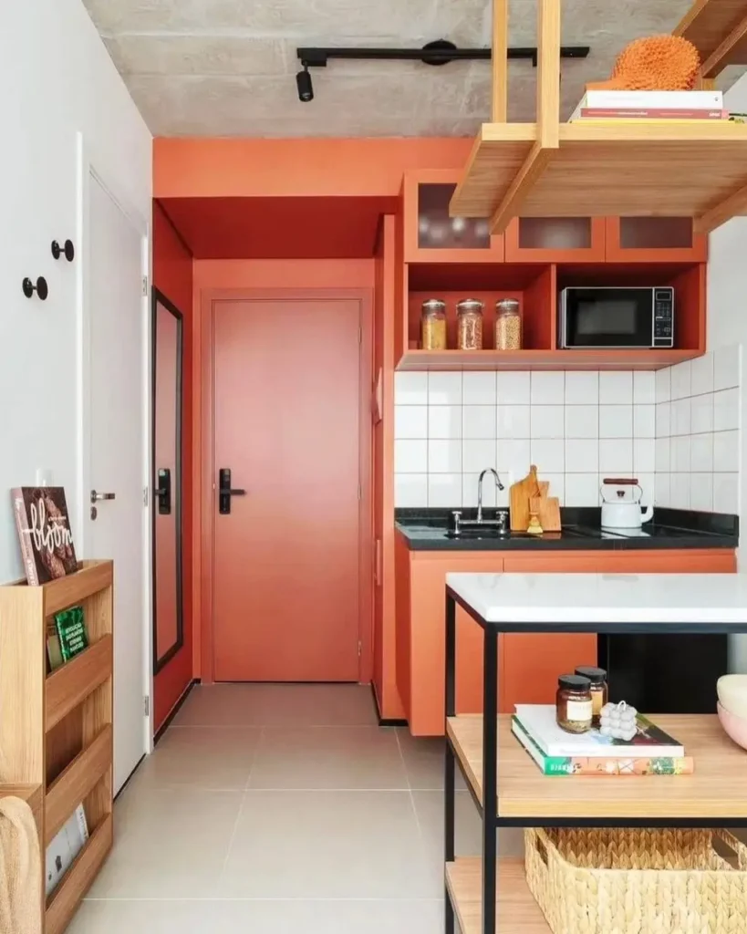 A tiny kitchen design featuring a bold terracotta color on the walls and cabinets.