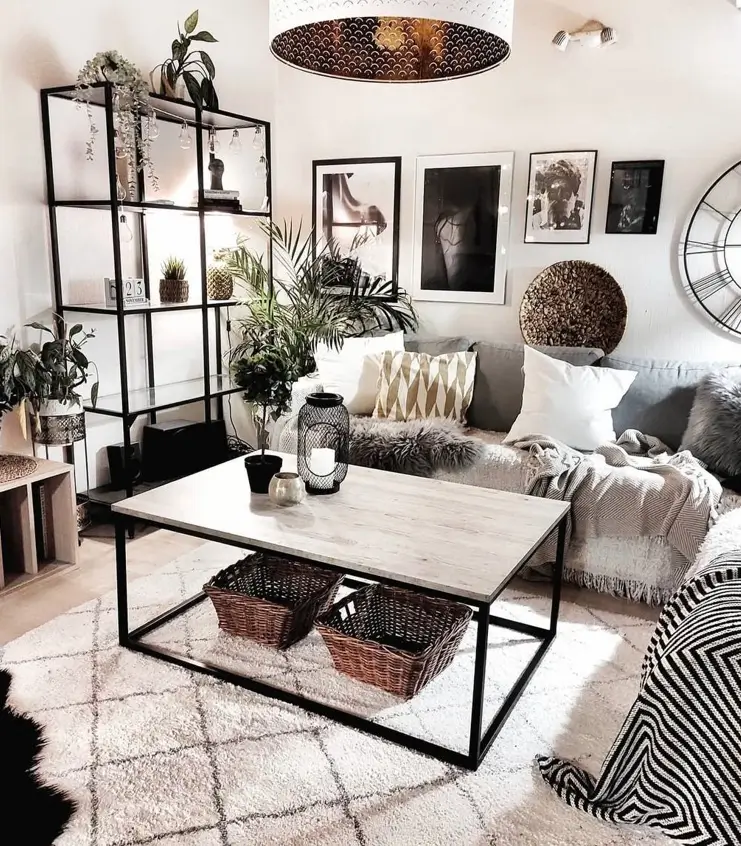 An industrial-boho living room featuring a black metal bookshelf, a plush rug, and a cozy gray sofa with a gallery wall.