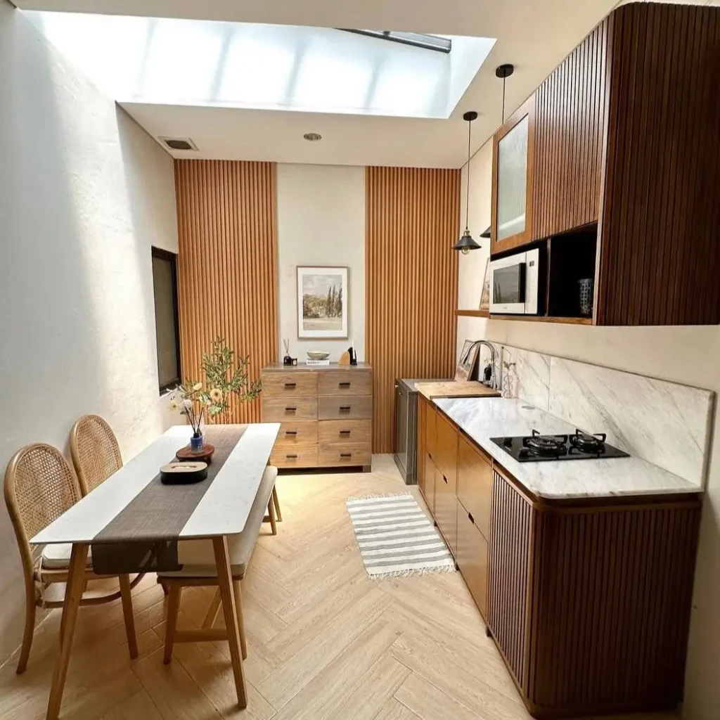 A modern small kitchen design with fluted wood cabinets and a large skylight.
