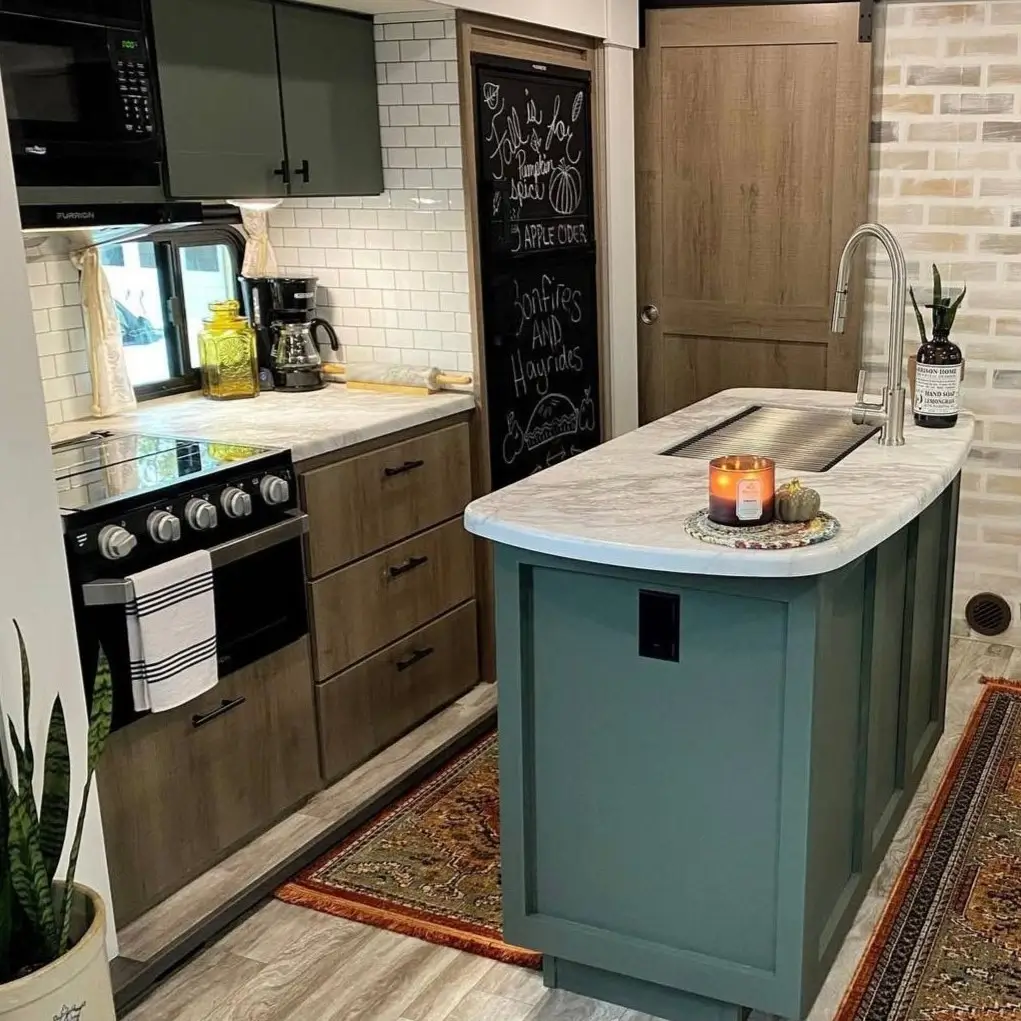 A small modern kitchen with a deep sage green island and rustic wood cabinets.