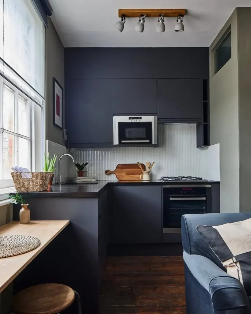 A modern small kitchen with minimalist dark gray cabinets and a white tile backsplash.
