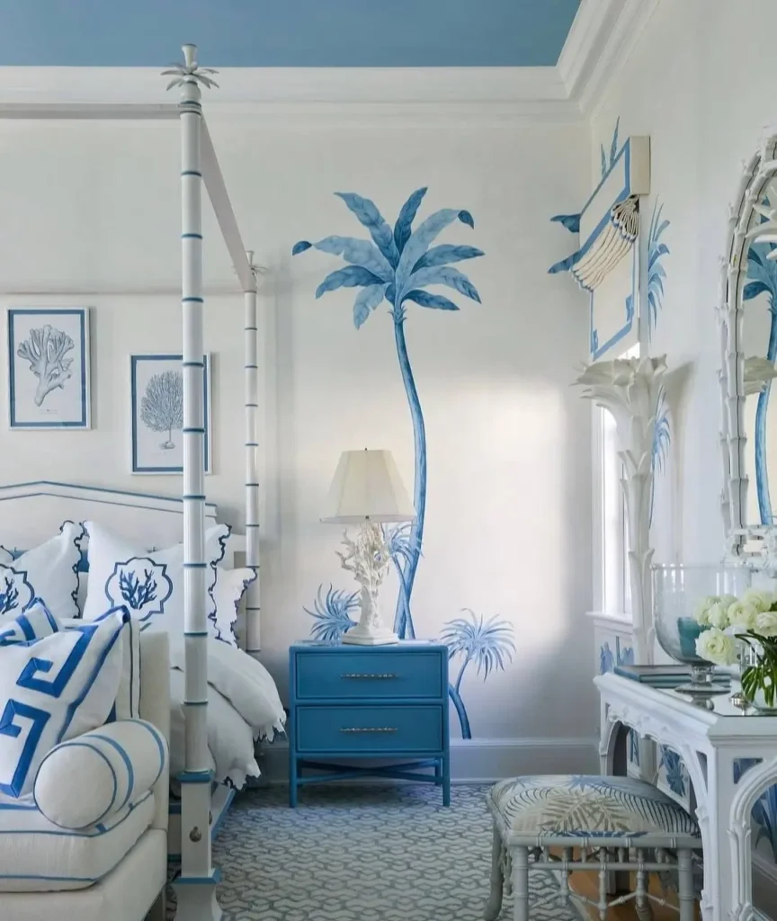 A glamorous beach themed bedroom with a hand-painted palm tree mural, white four-poster bed, and blue accents.