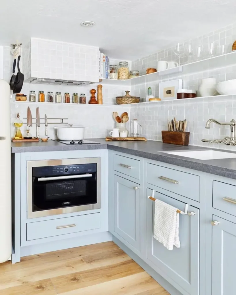 A small kitchen design featuring powder blue cabinets and a white mosaic tile backsplash.