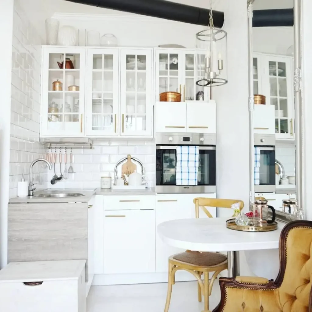 A tiny white kitchen design idea with a large floor mirror to expand the space.