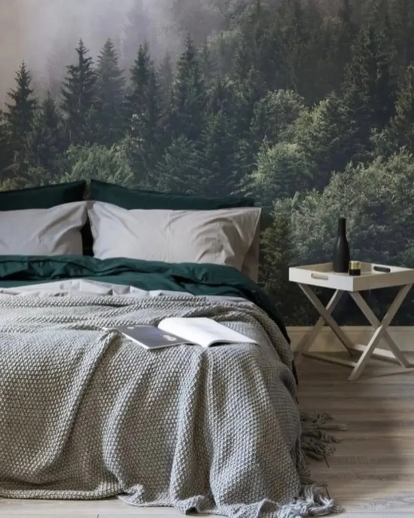 A modern bedroom featuring a large misty forest wall mural behind a bed with gray and dark green bedding.