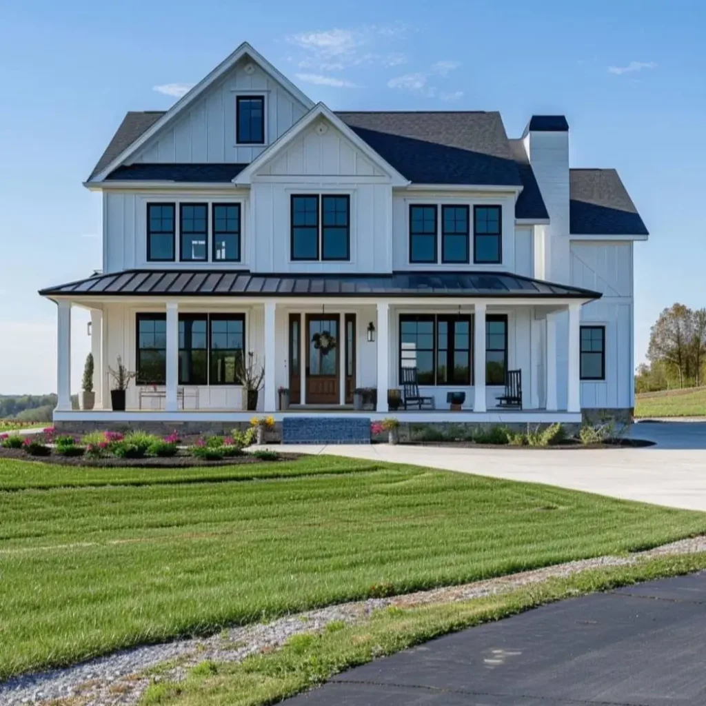 A stately modern white farmhouse featuring a prominent brick chimney, black windows, and a welcoming front porch.