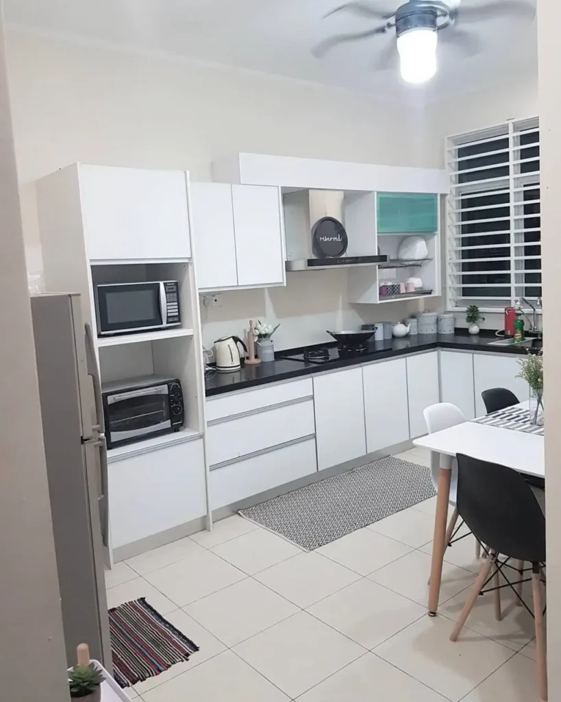A modern kitchen with white handleless cabinets, black countertops, and a tall appliance garage.