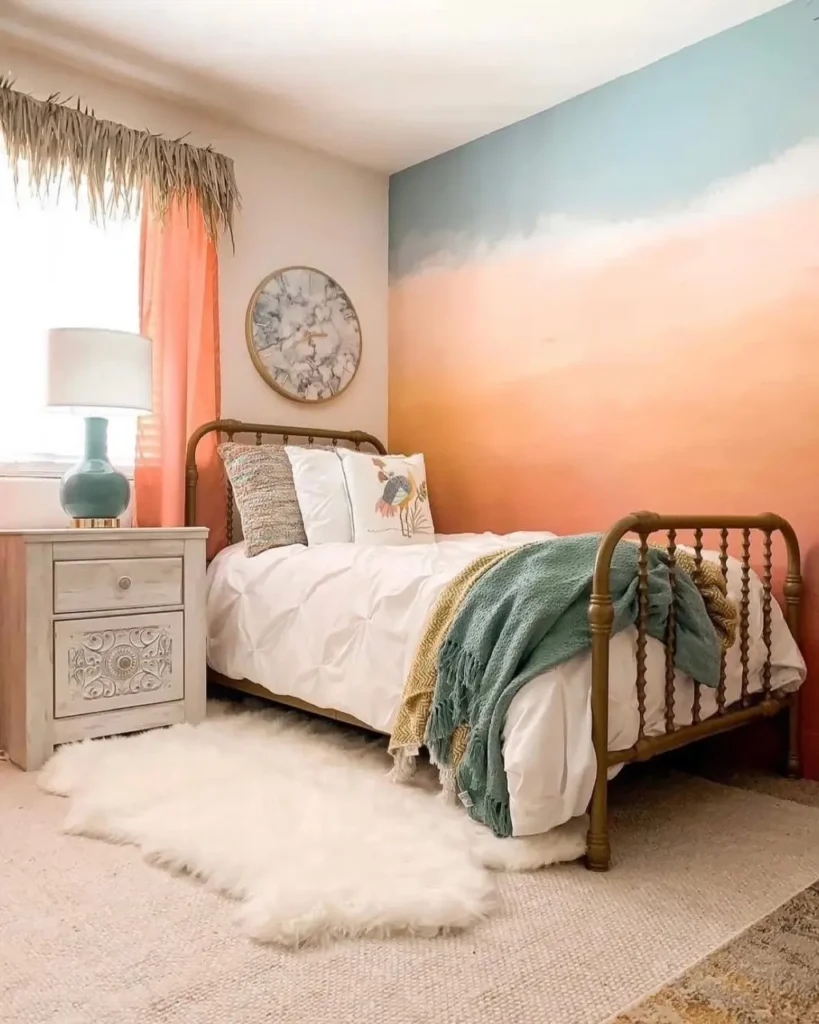 A bedroom featuring a sunset-inspired ombre accent wall that blends from coral to blue behind a metal bed.