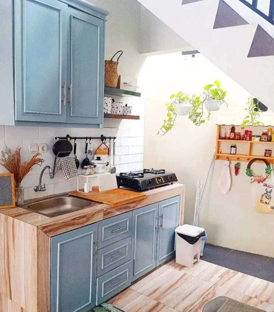 A tiny kitchen idea utilizing the space under a staircase with blue cabinets.
