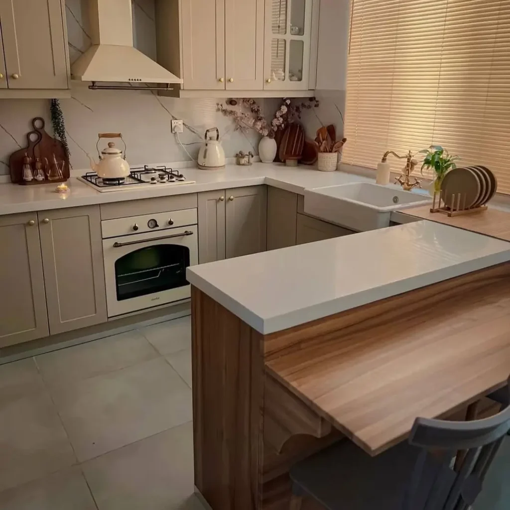 A small kitchen with beige shaker cabinets and a multi-level peninsula dining bar.