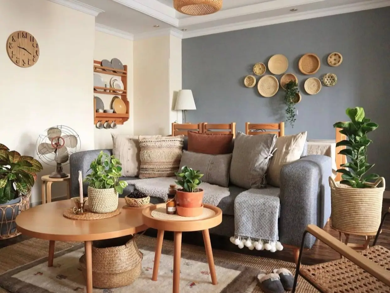 A cozy bohemian living room with a gray sofa, layered pillows, and a collection of woven wall baskets, showcasing inspiring bohemian living room decor ideas.