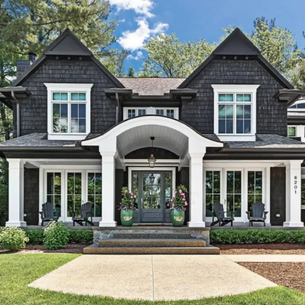 A stately black shingle house with white columns and trim, showcasing a modern take on classic architecture.