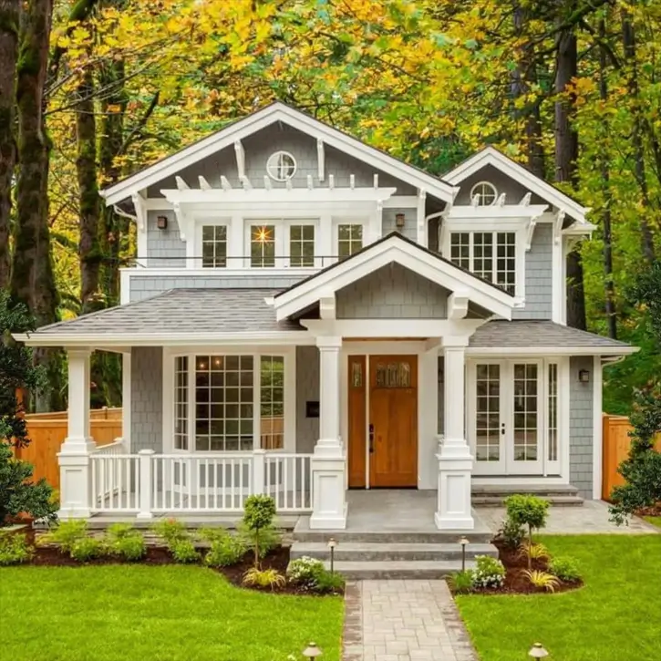A classic craftsman house exterior with gray shingle siding, a white covered porch with columns, and a natural wood front door.