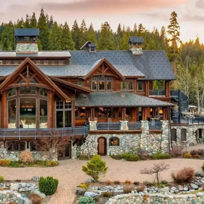 16 Mountain Mansions That Define Luxury Alpine Living 5 A classic mountain lodge mansion featuring a rustic combination of heavy timber framing and a rugged stone base, nestled in a forest.
