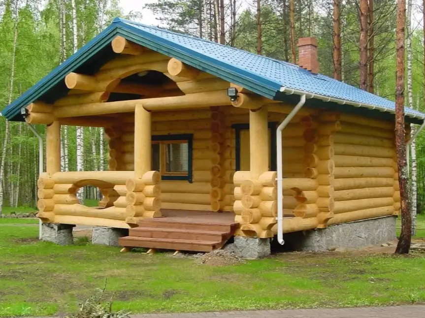 60 Charming Small Log Cabin Ideas to Inspire Your Rustic Retreat 3 A small log cabin design featuring large rounded logs, a blue metal roof, and a covered front porch.