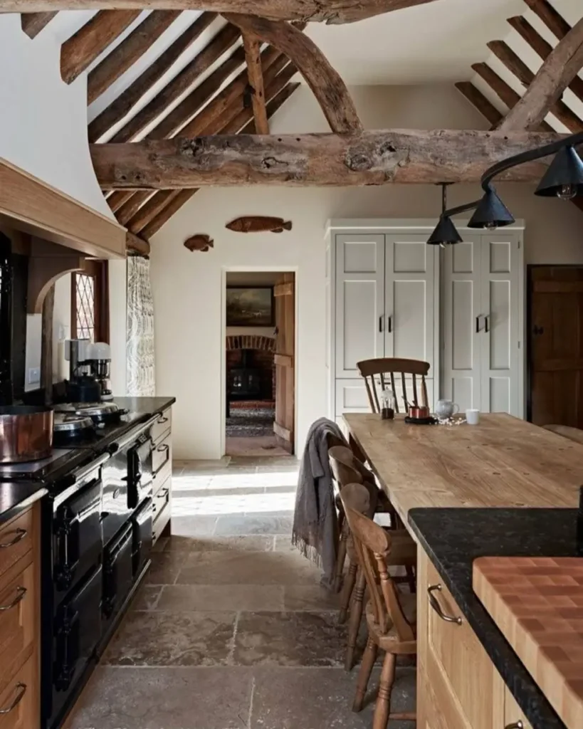 A rustic kitchen design in a converted barn with high vaulted ceilings and dramatic dark wood beams.