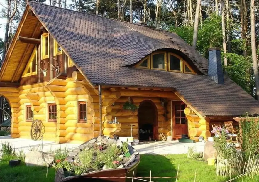 60 Charming Small Log Cabin Ideas to Inspire Your Rustic Retreat 12 A large, light-colored log cabin with a dramatic eyebrow dormer window and a dark tiled roof.