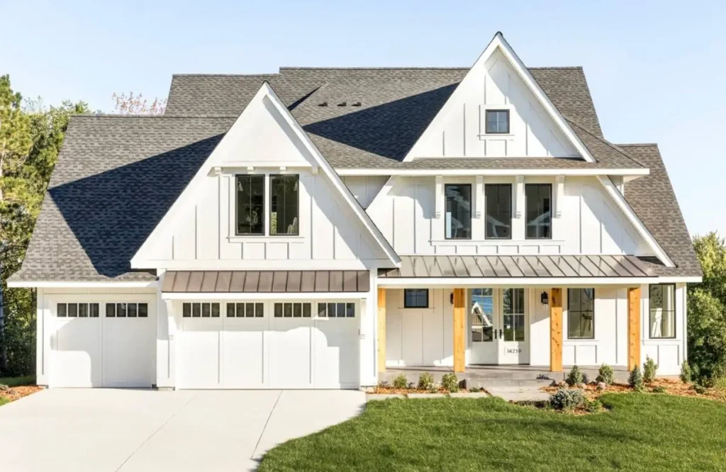 A modern off-white farmhouse with multiple gables, a dark gray shingle roof, and natural wood porch posts.