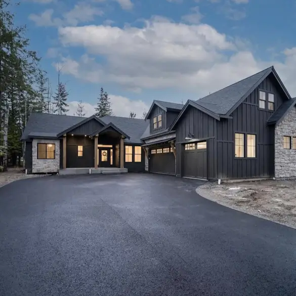 A modern black house exterior grounded by rugged natural stone elements, blending sleek and organic textures.