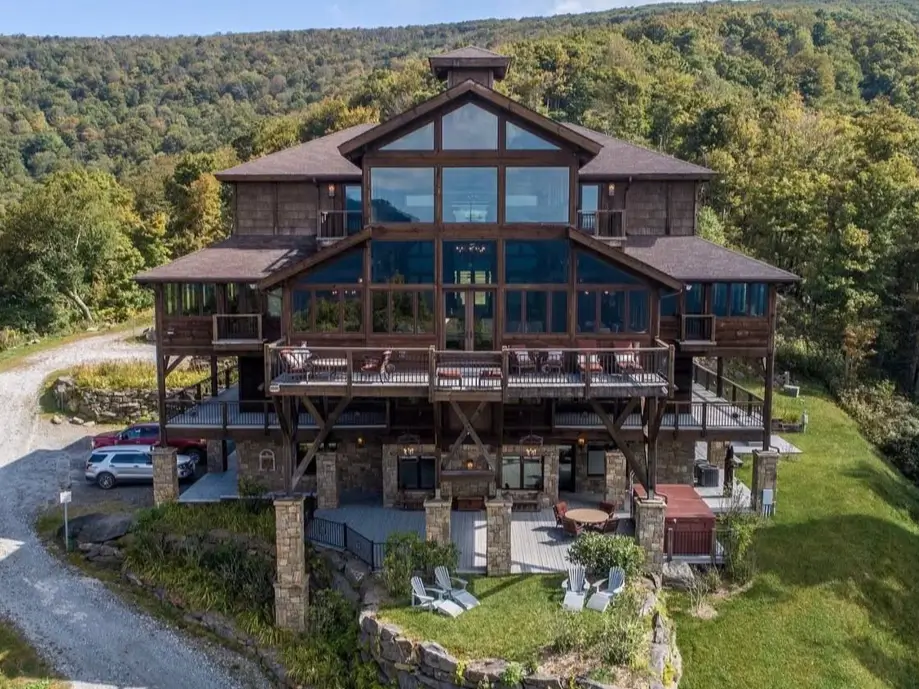 16 Mountain Mansions That Define Luxury Alpine Living 16 A towering wooden mountain mansion built with a vertical design on a steep slope, featuring multiple stories of decks overlooking the forest.