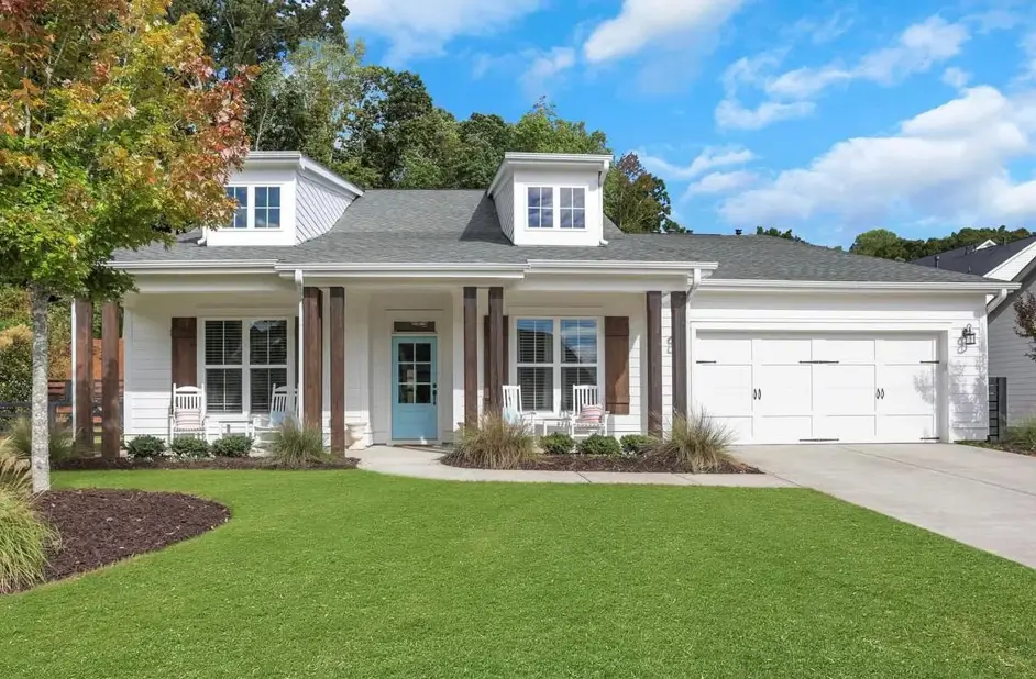 A white modern farmhouse ranch house with dark wood posts, shutters, and a light blue front door.