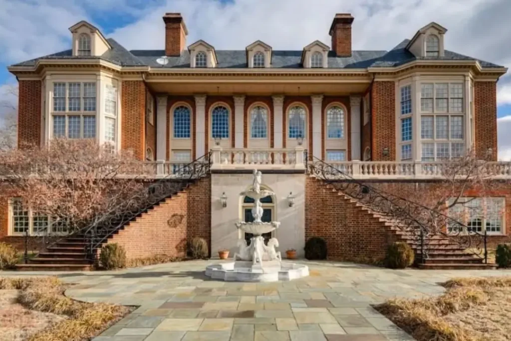 The Ultimate Guide to Luxury Mansion Design: 33 Ideas for Grandeur 16 The rear terrace of a brick mansion with dual staircases leading down to a garden fountain.