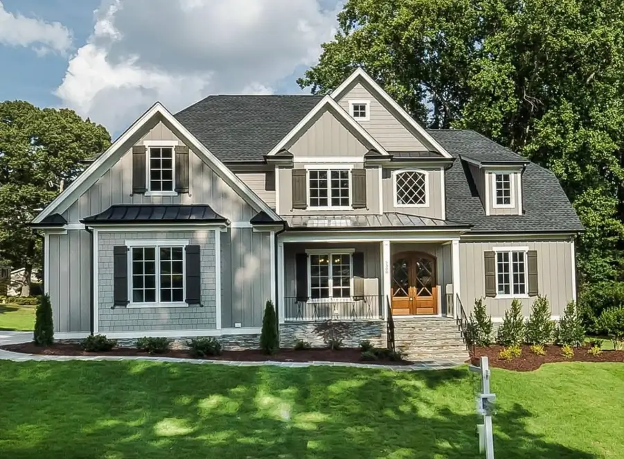 A modern craftsman house exterior with light gray siding, dark shutters, and warm wood double front doors.
