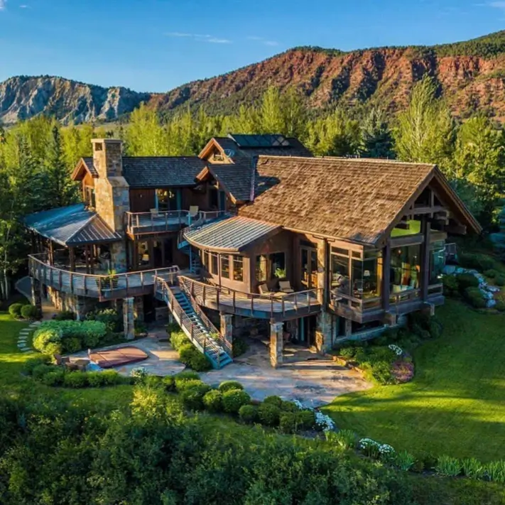 16 Mountain Mansions That Define Luxury Alpine Living 17 A luxury mountain home with multi-level tiered decks that follow the terrain, complete with an outdoor hot tub and panoramic views.