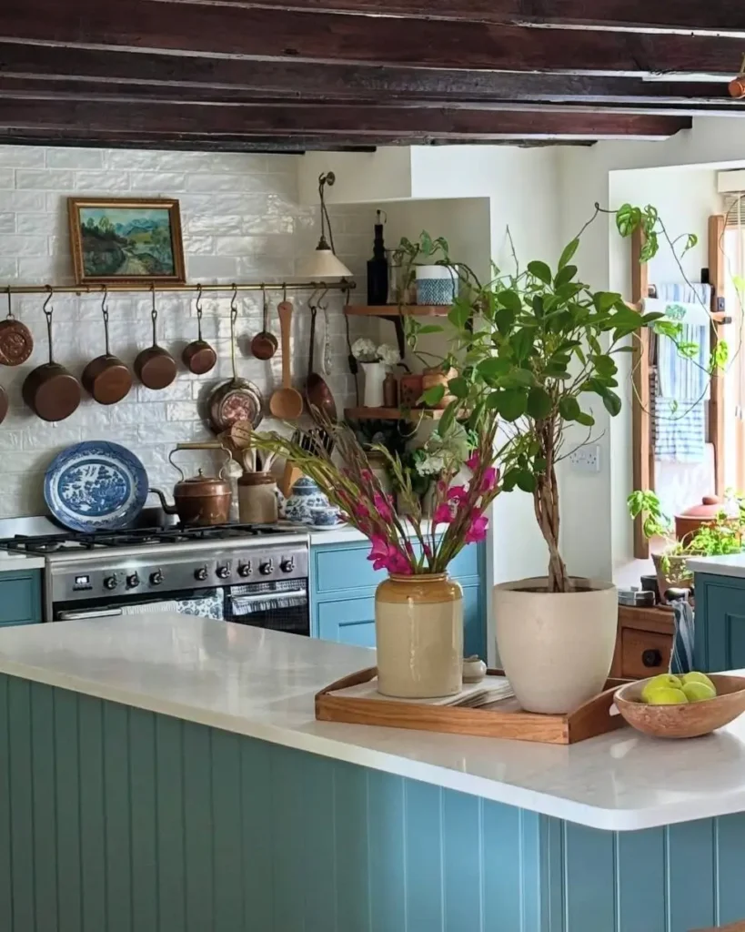 A rustic kitchen design featuring blue-green cabinets and an organized collection of copper pots hanging above the stove.