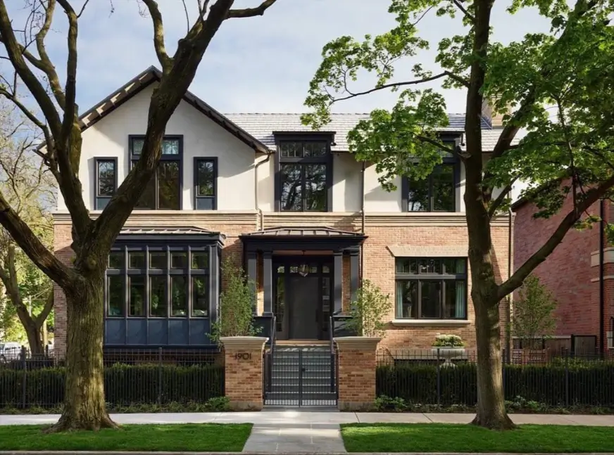 A modern craftsman house exterior with a light brick first floor, white stucco second story, and bold dark trim.