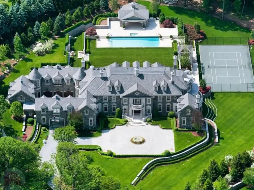 The Ultimate Guide to Luxury Mansion Design: 33 Ideas for Grandeur 19 An aerial view of a grand stone mansion compound with a pool and tennis court.