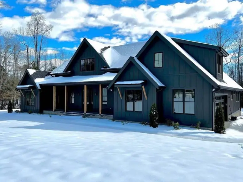 A modern black house exterior creating a striking visual contrast against a bright, snowy landscape.