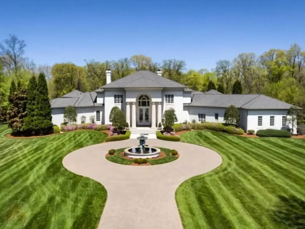 The Ultimate Guide to Luxury Mansion Design: 33 Ideas for Grandeur 20 A white luxury mansion with a symmetrical facade, circular driveway, and central fountain.