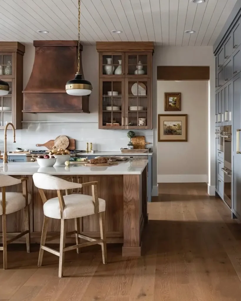 A modern rustic kitchen featuring a large custom copper range hood, wood island, and blue floor-to-ceiling cabinets.