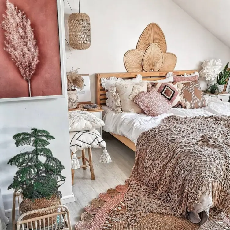 A cozy boho bedroom with three large, dried palm fans arranged on the wall above a wooden bed.