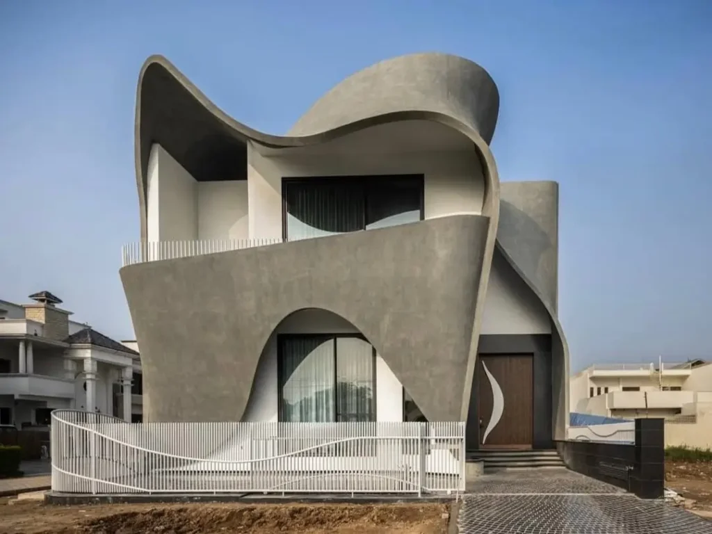 A contemporary concrete home with a dramatic, curving facade that creates sculptural balconies and archways.