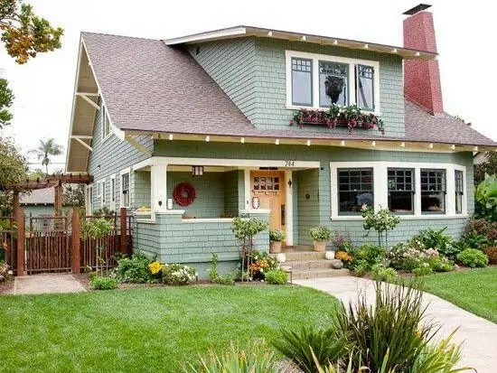A charming country house in the Craftsman style with sage green siding and a welcoming front porch.