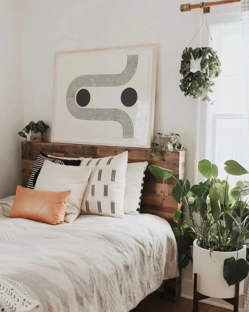 A cozy bedroom design with a rustic wooden headboard, modern black and white art, and patterned pillows on the bed.