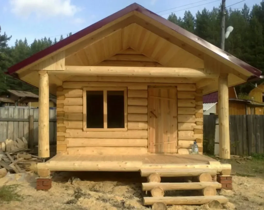 Small Log Cabins: 36 Ideas for Cozy Living & Enduring Charm 5 A newly built small log cabin with a covered porch, showcasing natural, light-colored wood.