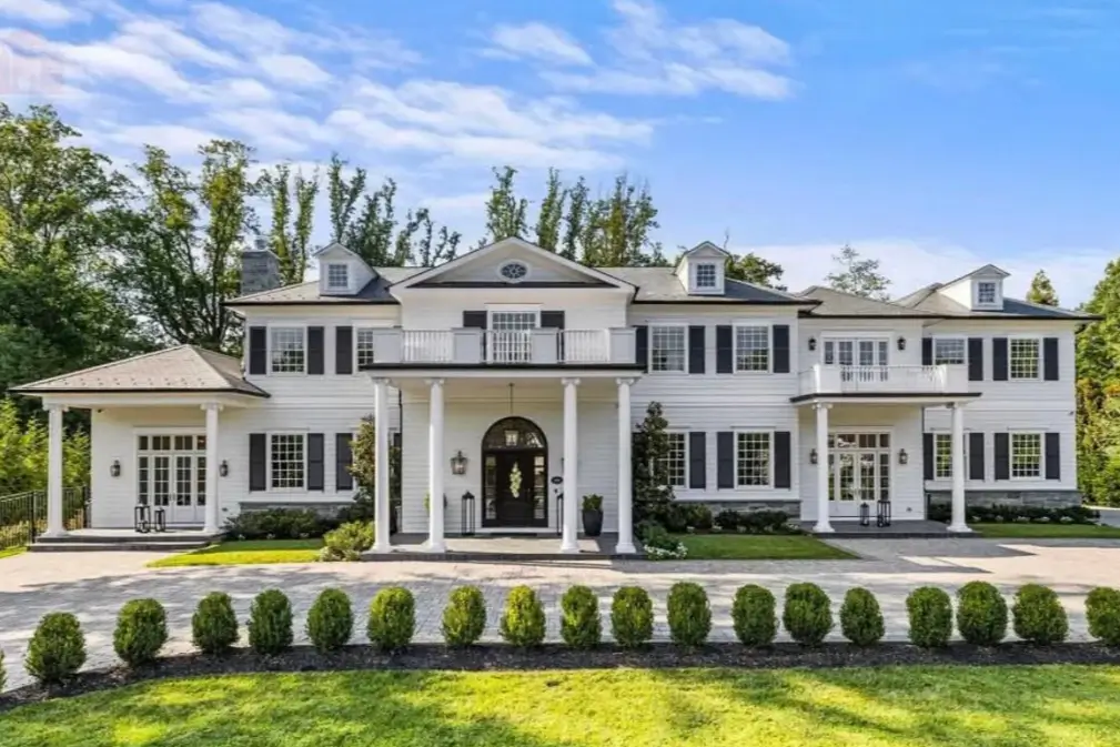 The Ultimate Guide to Luxury Mansion Design: 33 Ideas for Grandeur 5 A grand white colonial mansion with black shutters and stately columns lining the entrance.