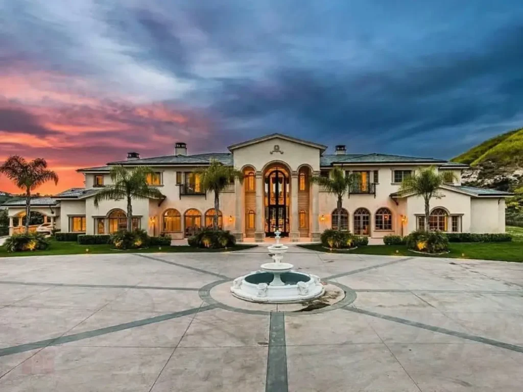 The Ultimate Guide to Luxury Mansion Design: 33 Ideas for Grandeur 23 A luxurious mansion with a central fountain and dramatic exterior lighting at sunset.
