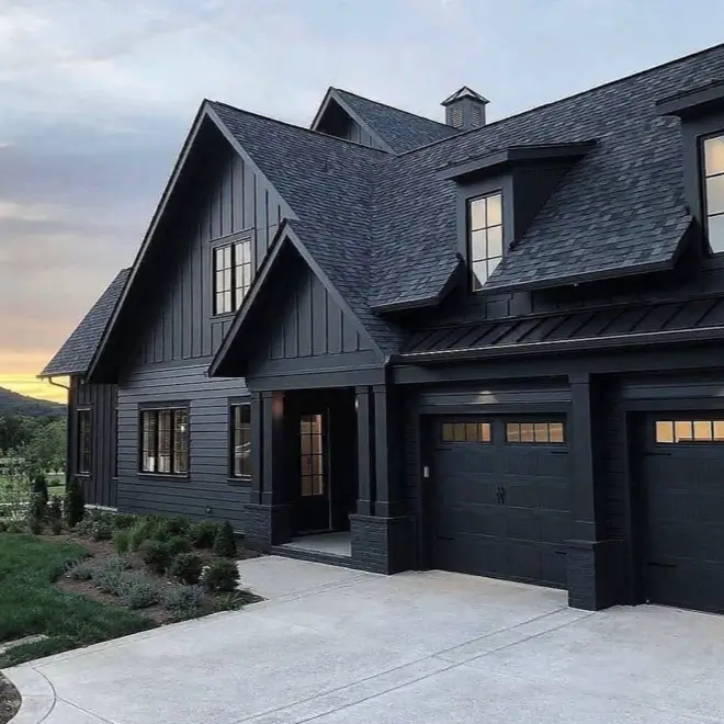 A modern black house with a cohesive monochromatic exterior, where the siding, roof, and garage doors are all dark.