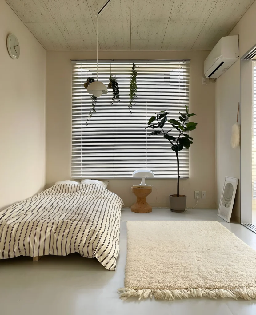 Minimalist bedroom with white walls and natural wood furniture.